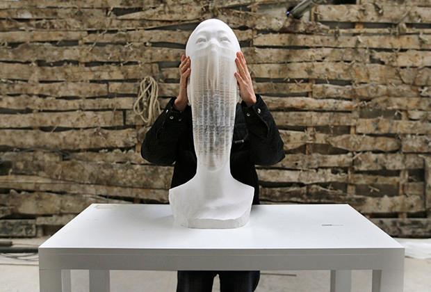 Chinese artist Li Hongbo shows his paper sculpture work, which is made of 6,000 pieces of paper, while raising it at his studio on the outskirts of Beijing, January 20, 2014. Born into a simple farming family, Li said he had always loved paper, invented in ancient China. Beyond his sculptures, he has spent six years producing a collection of books recording more than 1,000 years of Buddhist art on paper. Neither plaster nor clay, the statues are concertinas of thousands upon thousands of fine pieces of paper."At the beginning, I discovered the flexible nature of paper through Chinese paper toys and paper lanterns," Li, 38, told Reuters. Picture taken on January 20, 2014. REUTERS/Jason Lee (CHINA - Tags: SOCIETY) - RTX17QY9