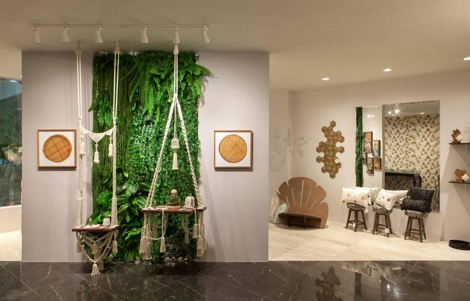 Pop Up Store - Marcela Carvalho. Em um único ambiente, a profissional que assina o projeto une duas lojas pautada pelo tema da mostra, Foco no Essencial. Sem excessos, o espaço conta com um paisagismo de ponta, com jardim vertical e terrários. Destaque para as peças em Macramé, uma técnica milenar totalmente manual, que pode ser vista no balanço, luminárias e mesas de apoio. A decoração possui ainda revestimento 3D e pisos de tons diferenciado, demarcando cada loja. 