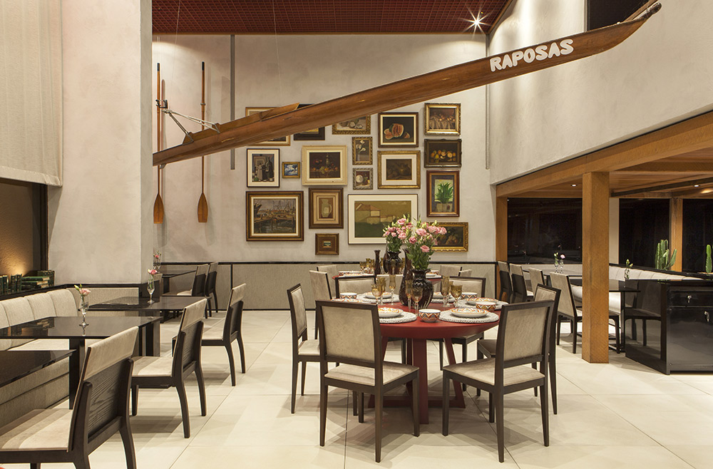 Restaurante - Sérgio Paulo Rabello. A casa de massas ganha uma versão contemporânea, inspirada na localização em frente ao mar. Por isso, faz sentido a canoa de competição, chamada skiff, suspensa no espaço. Sua matéria-prima, a madeira, inspira uma cobertura intimista que delimita outra área. As paredes forradas em tecido, o piso e até o estofamento das cadeiras foram neutralizados e seguem um elegante tom de cimento queimado.