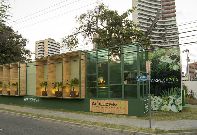 Calçada, Fachada e Estar de Entrada - Roberto Pamplona Jr. A sequência de nichos verticais em madeira reflorestada pinus compõe o fechamento - e cada nicho guarda um vaso em terracota com palmeiras. O mesmo verde das folhagens colore a estrutura metálica de sustentação e os muros.