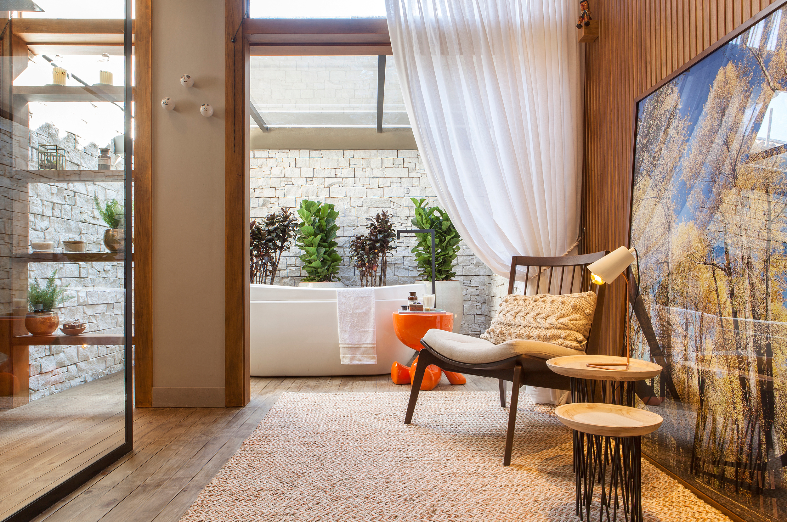 <span>Sala de Banho do Casal - Elaine Queçada e Juliana Brigagão. Materiais naturais e a diversidade de plantas levam a natureza para dentro de casa, um refúgio relaxante com conforto e bem-estar. A banheira de imersão é a protagonista do ambiente, que é totalmente integrado pelo uso contínuo do deck de madeira. Os tons neutros valorizam a luz natural </span><span>no espaço.</span>