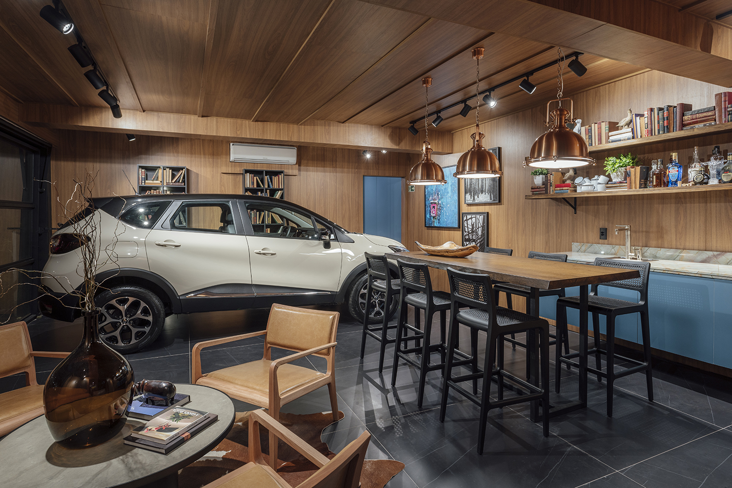 Garagem Renault Home SPA - Luiz Sentinger. Estes 60 m² combinam espaço gourmet com bar e sala de banho com SPA. Teto e paredes ganham painéis de MDF no padrão freijó, da Duratex. Já a bancada é de madeira maciça, acompanhada pelas banquetas Liv, de Luan Del Savio. Ele também assina as cadeiras em jequitibá e couro caramelo ao redor da mesa de centro Concrete, de Diogo Tomazzi.