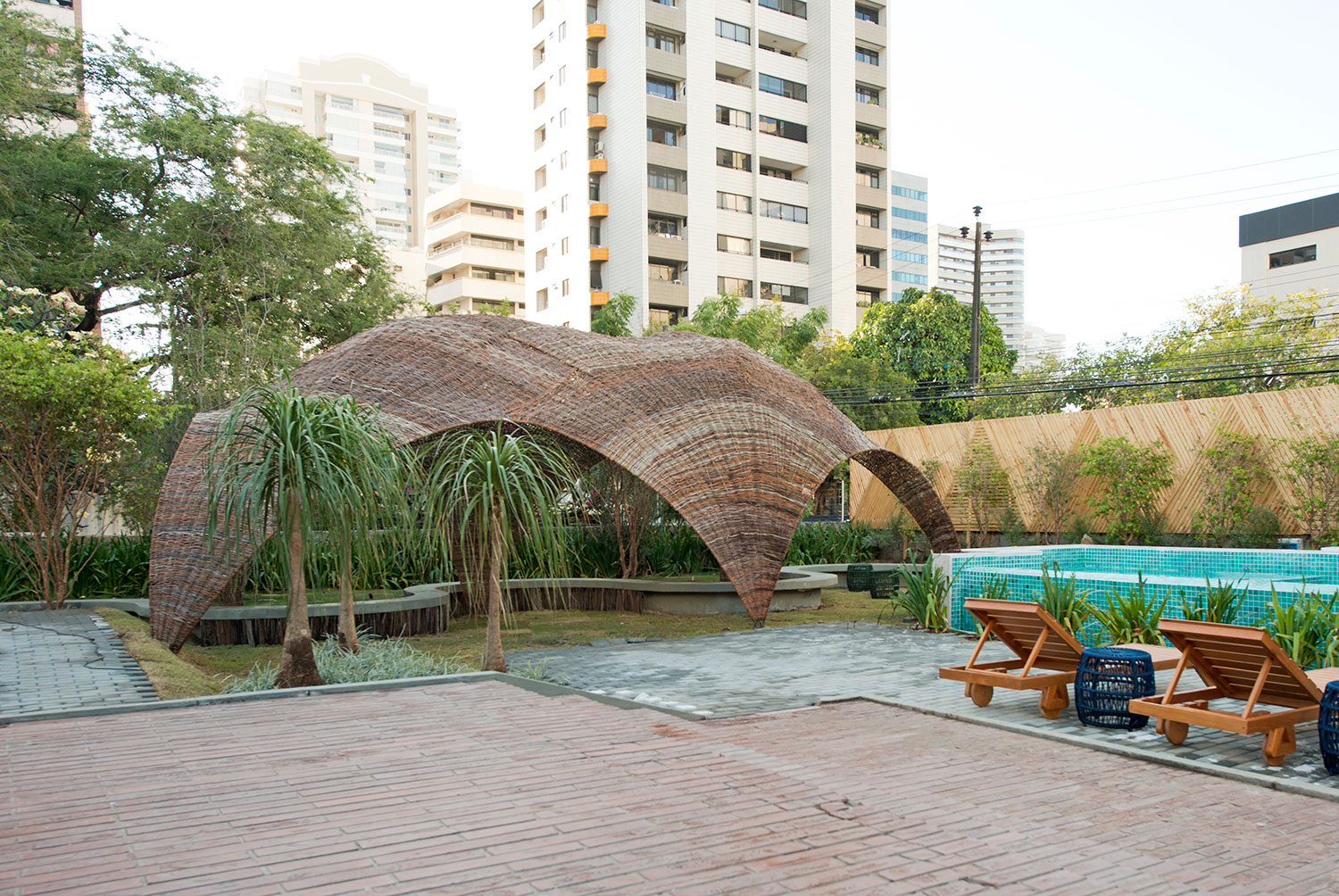 Jardim com Piscina - Arthur Bonavides, Bruno Frota e Carlos Zaranzza. Tendo como ponto de partida a espiritualidade, o ambiente tem como objetivo proporcionar uma fuga do estresse e da correria do dia a dia. Para tal escape, o trio de profissionais explora a vegetação e cria um espaço dedicado à meditação e à busca pela paz interior. Um dos destaques é o uso de elementos que fazem referência, de forma sucinta, aos quatro elementos - água, fogo, terra e ar. Outro diferencial é a oca, feita de maneira conceitual com materiais como bambu, localizada em meio à natureza de um jardim verde e com a intenção de proporcionar conforto, comodidade e bem-estar.