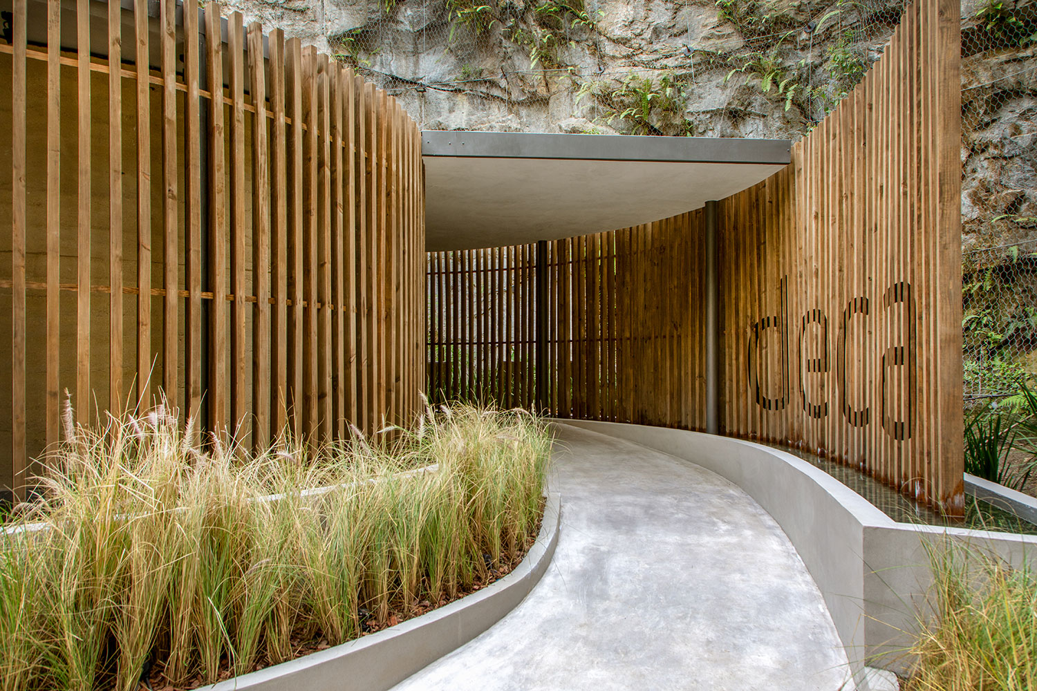 CASACOR Rio de Janeiro 2018: <span>Espaço Deca, A origem - Duda Porto. Ao lançar mão da arquitetura orgânica, Duda estabeleceu uma conversa com o entorno e criou um lugar de relaxamento, no projeto que celebra a parceria de 25 anos de CASACOR com a Deca. A construção em formato de espiral tem uma “casca” feita de brises de madeira de reflorestamento, que flutuam sobre o espelho d´água. Os brises permitem a visão dos produtos, sob uma nova perspectiva. No núcleo do espaço, paredes curvas em taipa de pilão.</span>