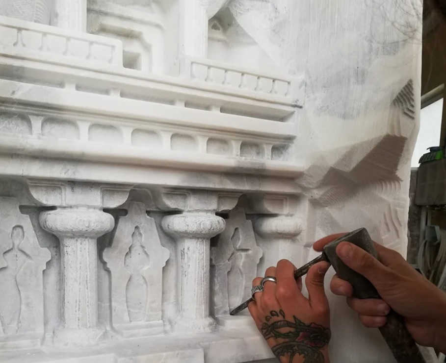 Mãos de artesão esculpindo mesa em mármore branco