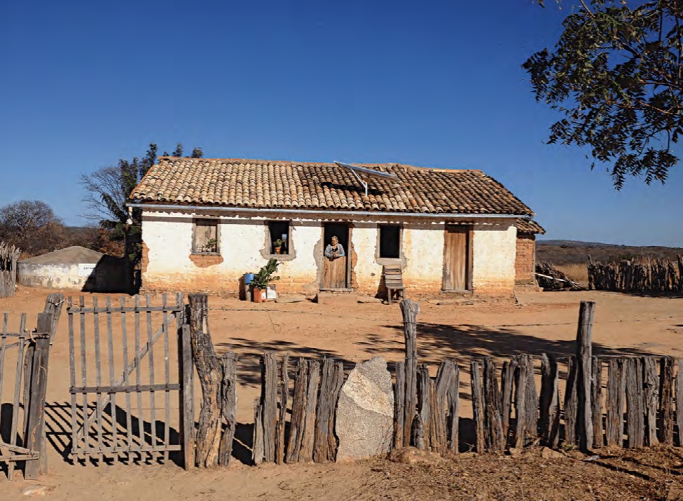 Casa simples no sertão com senhora olhando pela janela