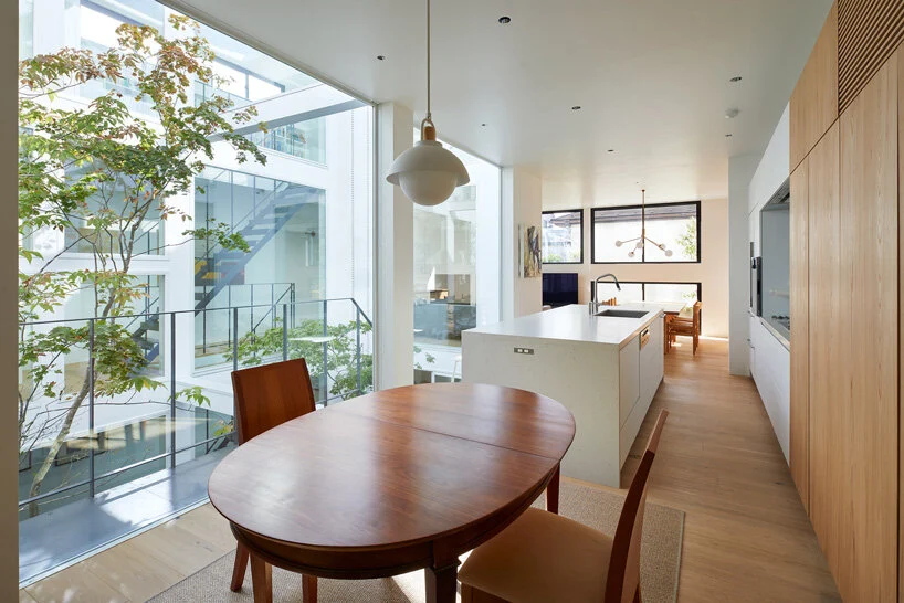 integração da sala de jantar com sala de estar. No centro uma mesa de madeira e ao lado as paredes são cobertas por um armário em marcenaria, deixando o projeto minimalista mais prático