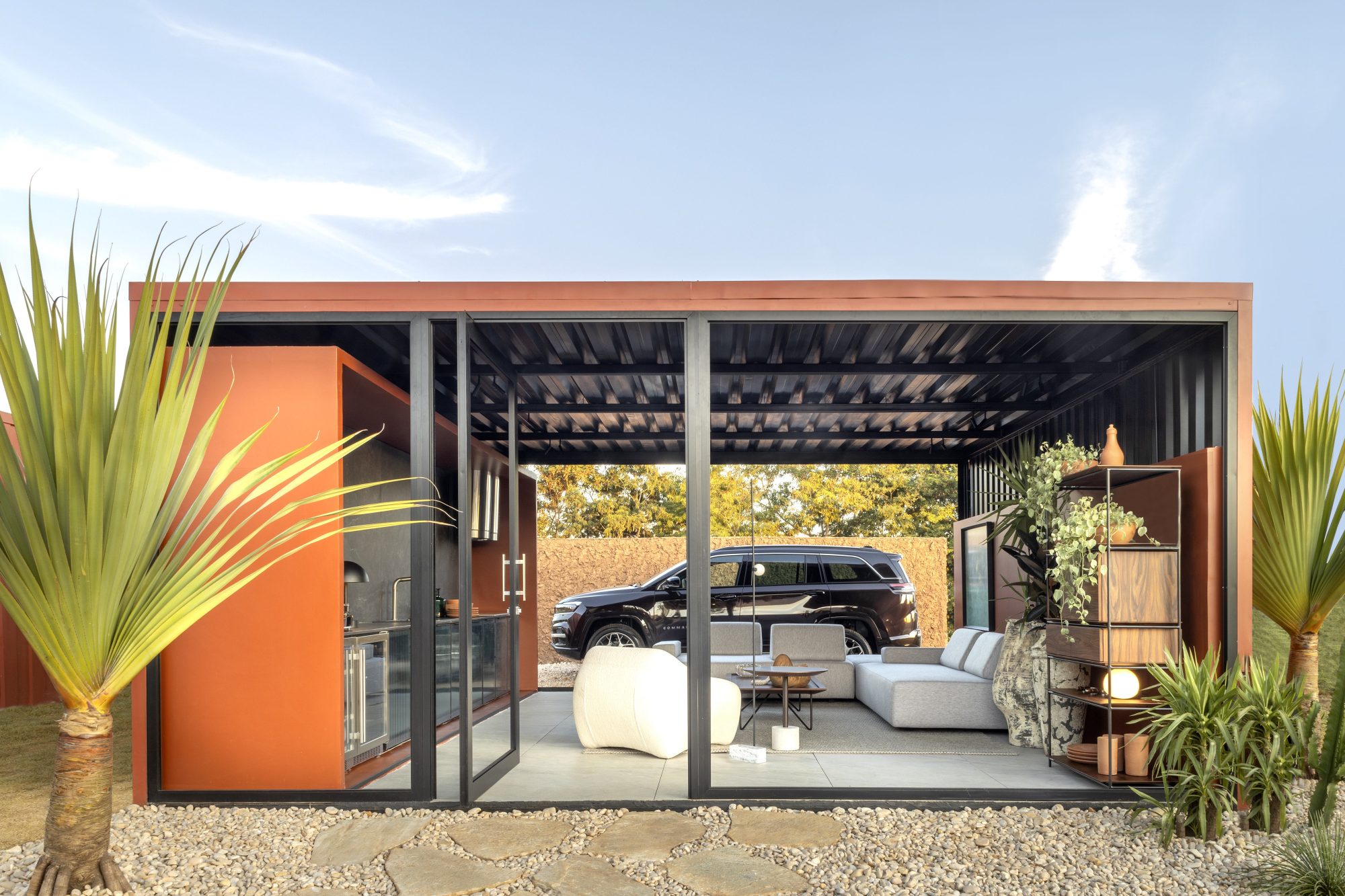 Marka Arquitetura- Garagem Estúdio do Viajante. Os arquitetos Kaio Vilanova e Manoel Figueiredo criaram um ambiente masculino, para um homem que adora viajar, curtir a natureza e se reunir com amigos para compartilhar suas experiências. Inspirado no Jalapão, o ambiente é uma garagem estilo loft, com área de estar e convivência e, por isso, o carro tem local de destaque. Remetendo a um dos principais pontos turísticos do Jalapão, a Pedra Furada, a parede de fundo foi revestida com barro. A área de estar e convivência conta com um pequeno apoio de cozinha, adega e cervejeira. Os tons de terracota se complementam à iluminação dramática e sóbria, às peças de design e às obras de arte. 