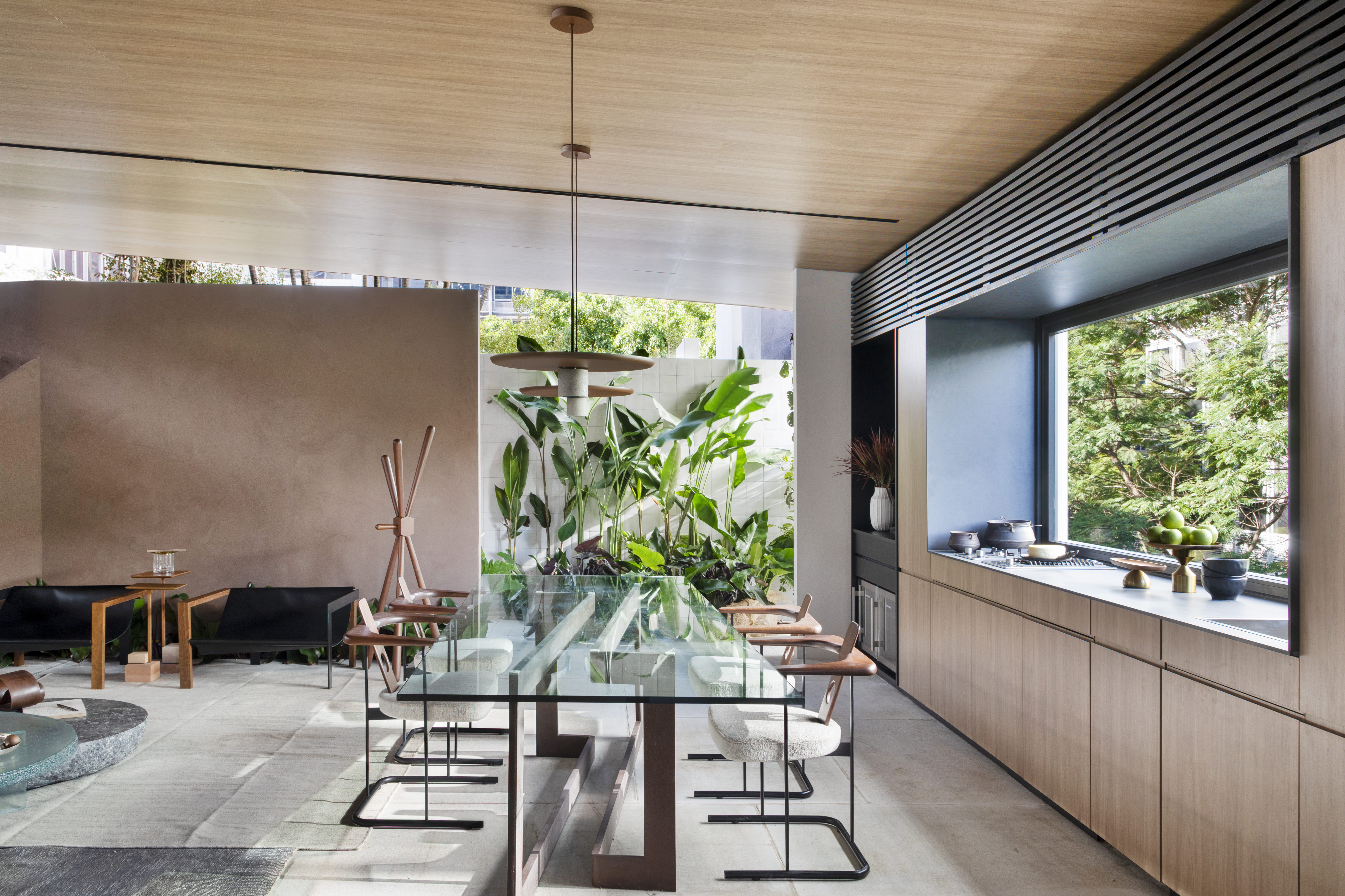 Navarro Arquitetura - Casa Araxá. Projeto da CASACOR São Paulo 2023. NA foto, sala de jantar com mesa de vidro, cozinha e jardim.