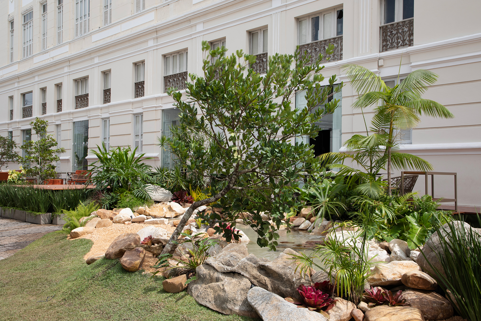 Atmosphera Plantas & Paisagismo - Praça Recentro - Verde em Poesia. Assim como a poesia é a arte de compor e escrever versos, o paisagismo é a arte de transformar o espaço proporcionando uma conexão maior com a natureza. O projeto da Praça Recentro – um espaço totalmente público, patrocinado pela Prefeitura da Cidade do Recife – baseou-se na harmonia entre tons de verde, texturas, formas e disposição da vegetação em uma escala rítmica no espaço, trazendo vivacidade e “poesia” para o Chanteclair.