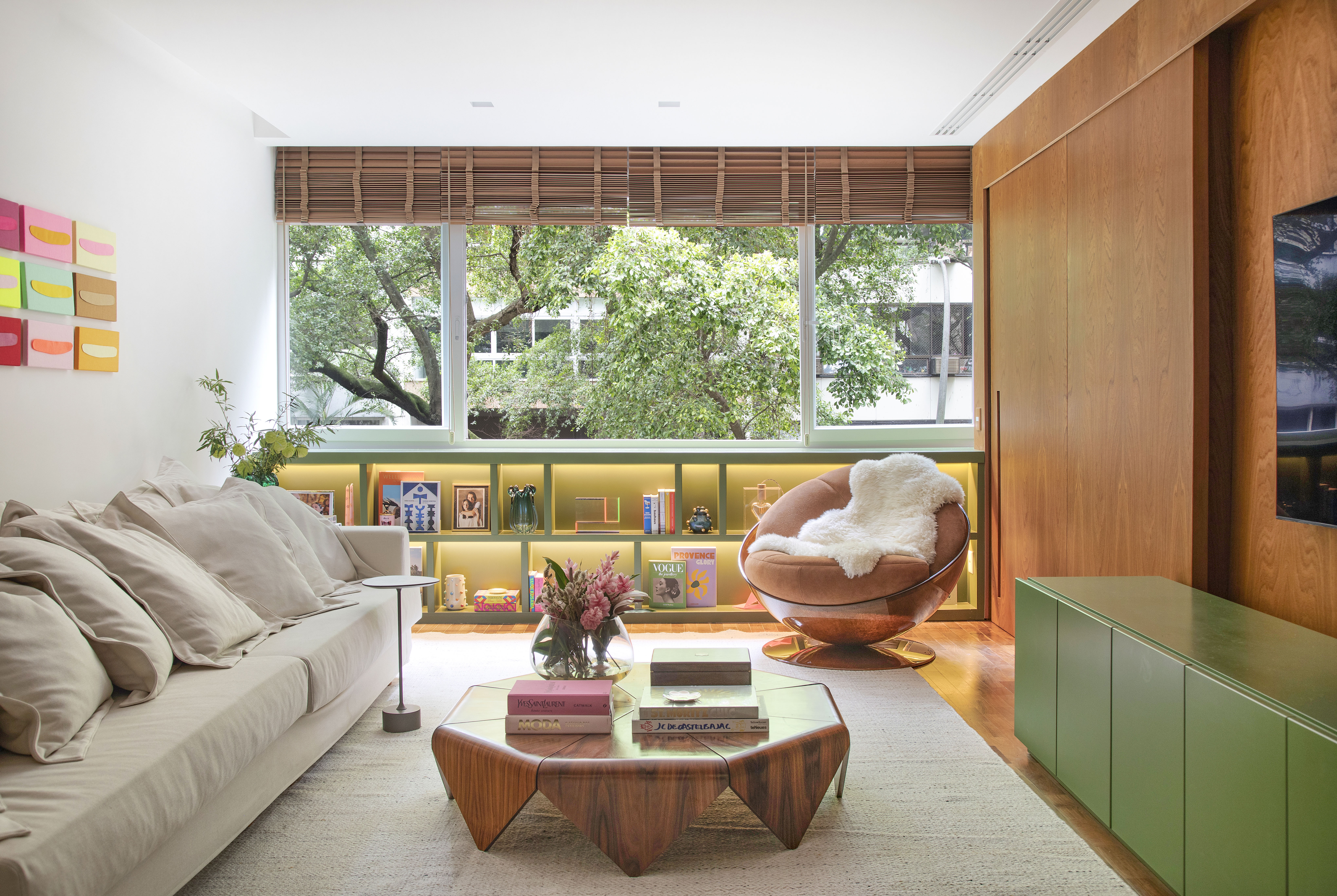 Apartamento em Ipanema é repleto de mobiliário de design brasileiro. Projeto de Bianca Da Hora. Na foto, sala de estar e jantar com parede de madeira e buffet verde.