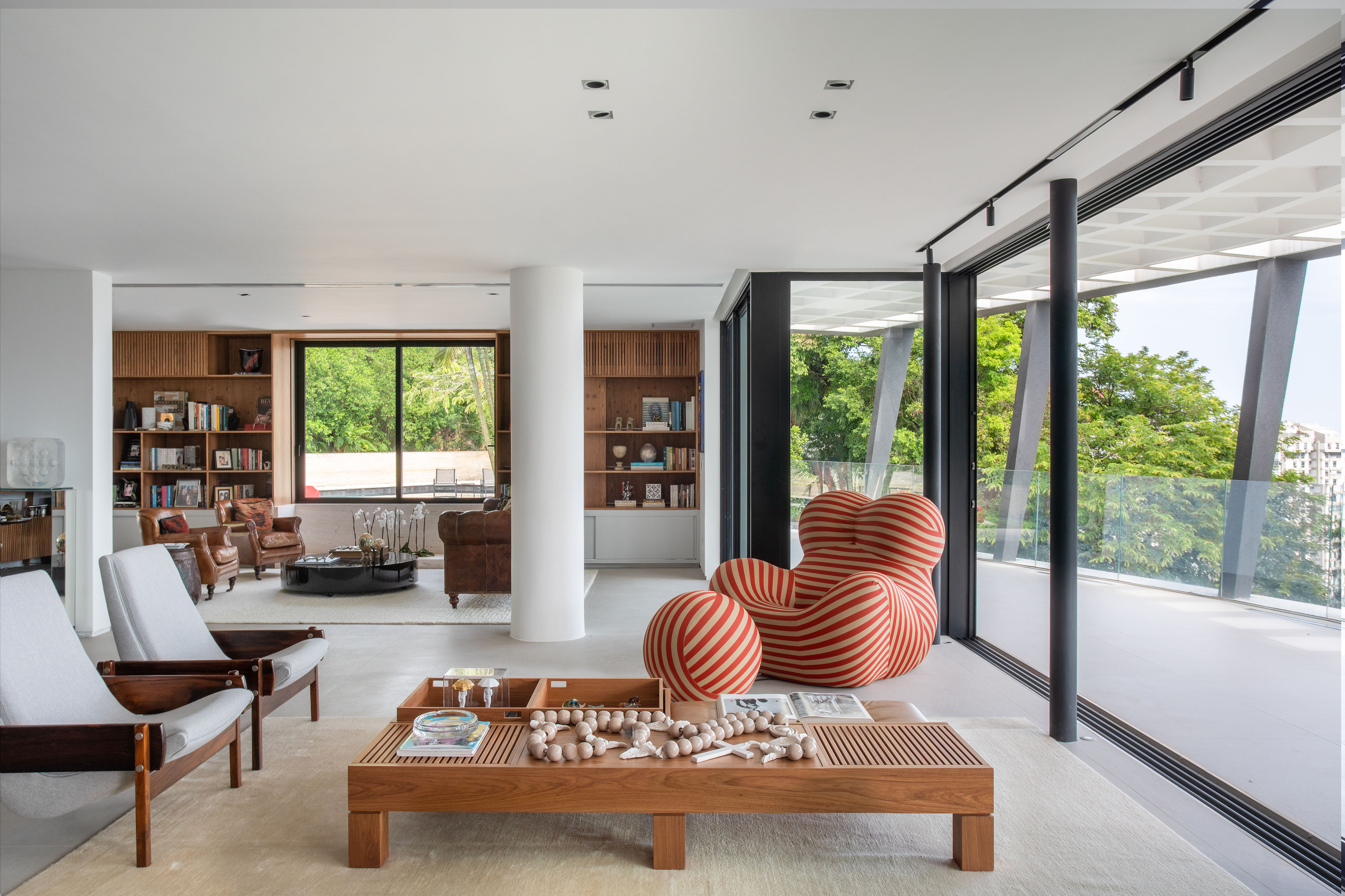 Reforma em casa modernista carioca valoriza sua arquitetura original. Projeto de Murad + Sarriá Arquitetura e de Renata Zappellini. Na foto, sala com poltrona up. estante e vista para o jardim.