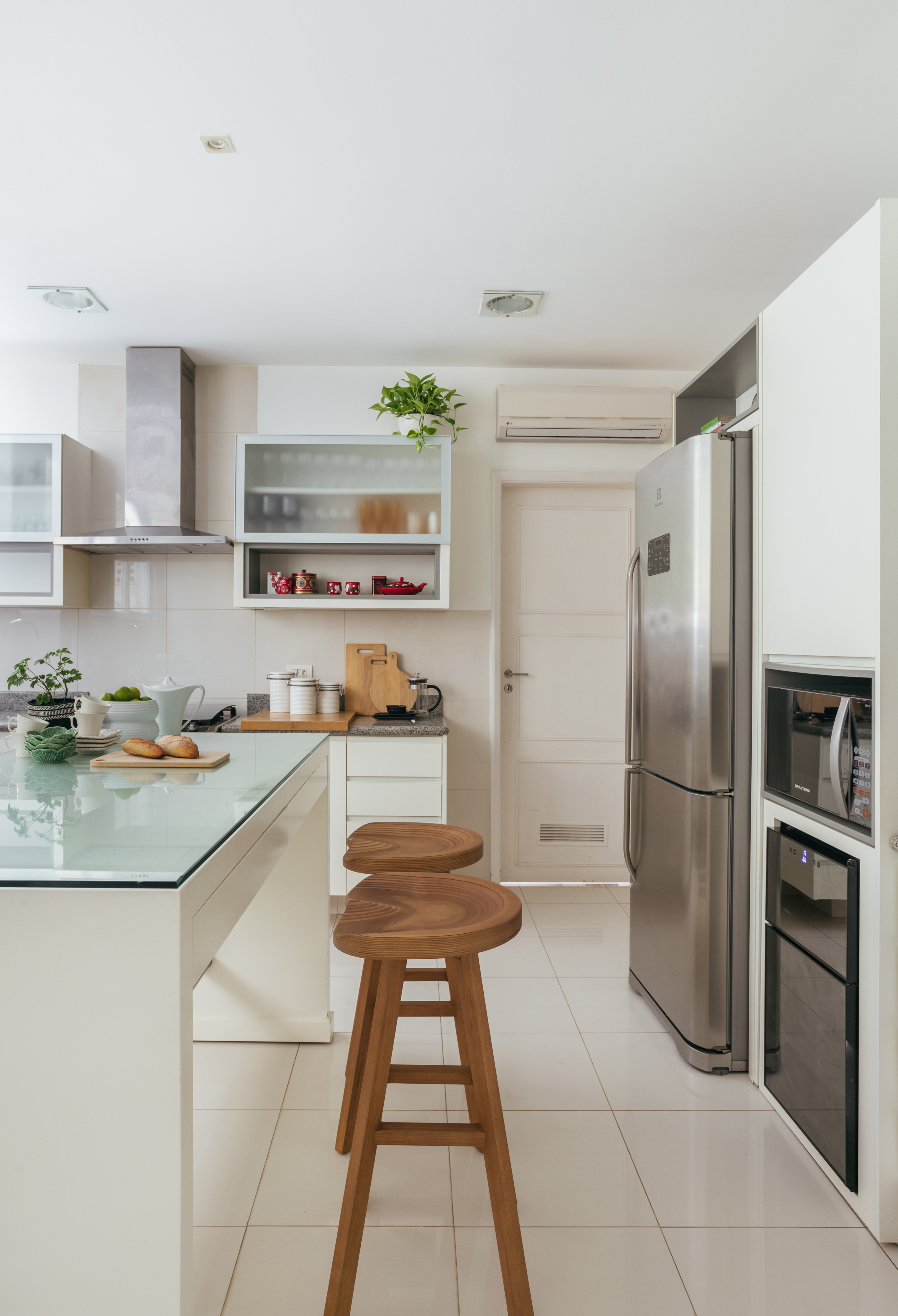 A natureza carioca circunda todo este apartamento de 245 m². Projeto de Vivian Reimers. Na foto, cozinha com ilha, banquetas e armários.