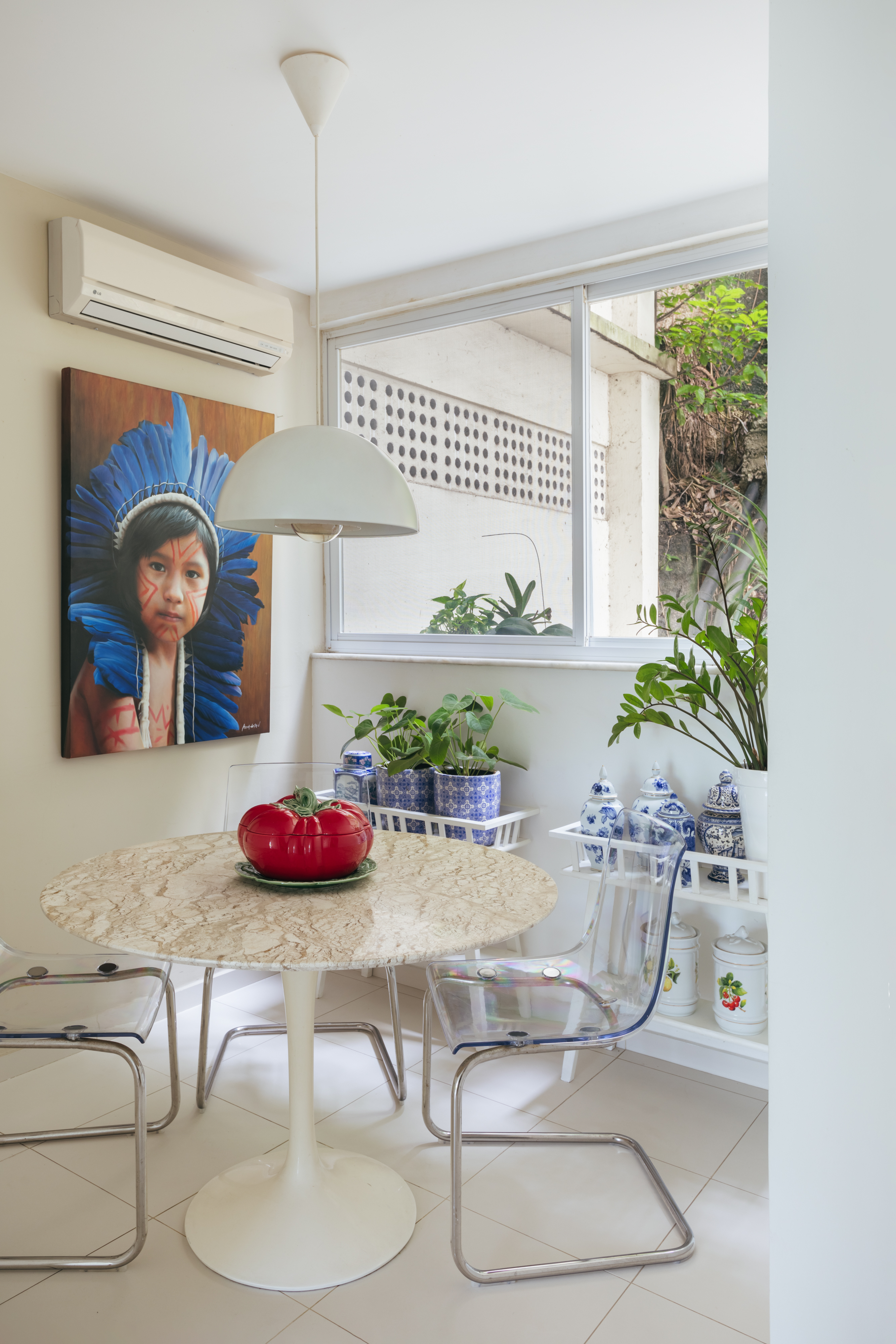 A natureza carioca circunda todo este apartamento de 245 m². Projeto de Vivian Reimers. Na foto, sala de jantar com mesa redonda, prateleiras e plantas.