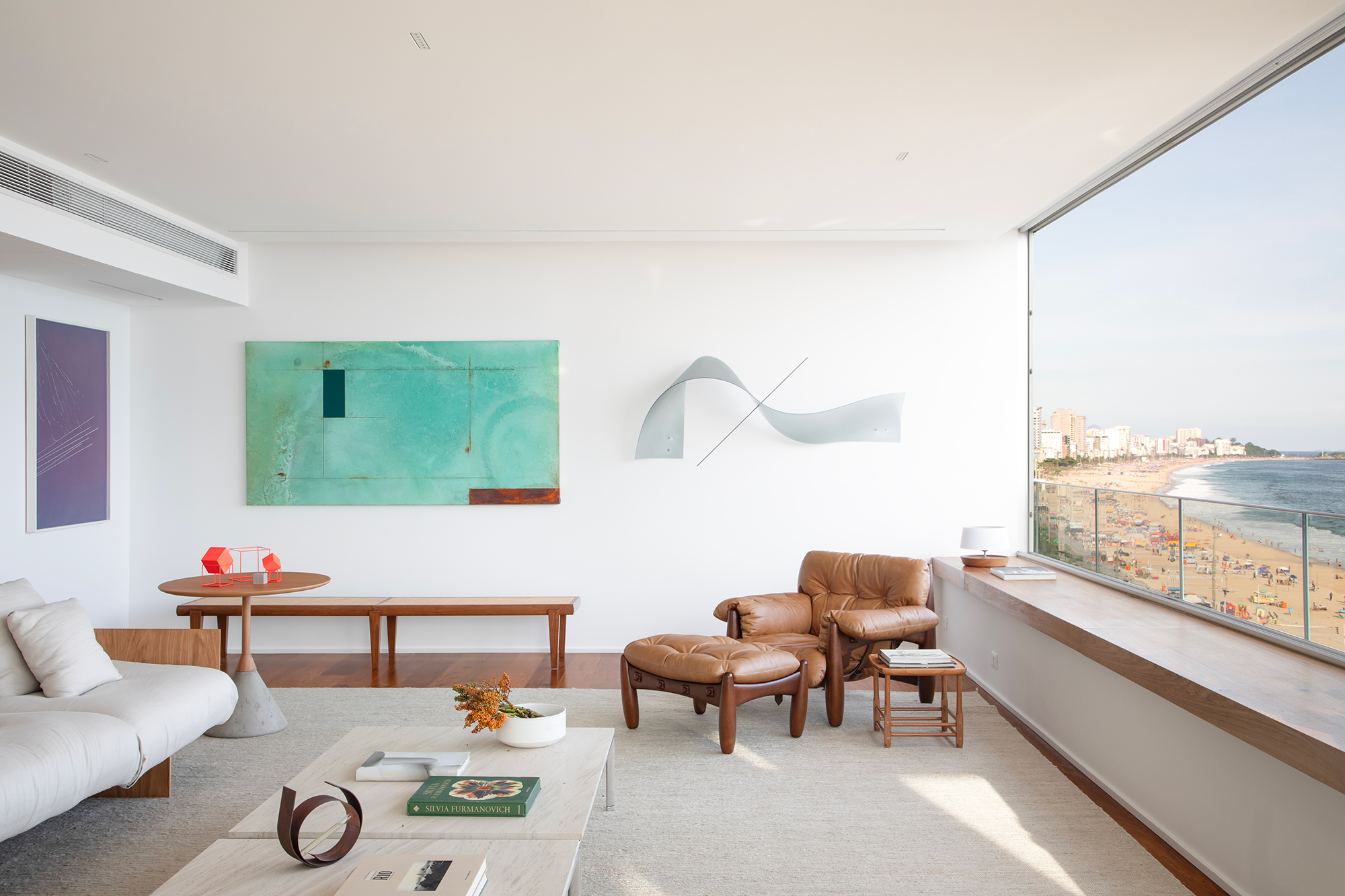 À beira-mar, apartamento minimalista ganha ares de galeria de arte. Projeto de João Panaggio. Na foto, sala de estar com quadro, poltrona mole e aparador.