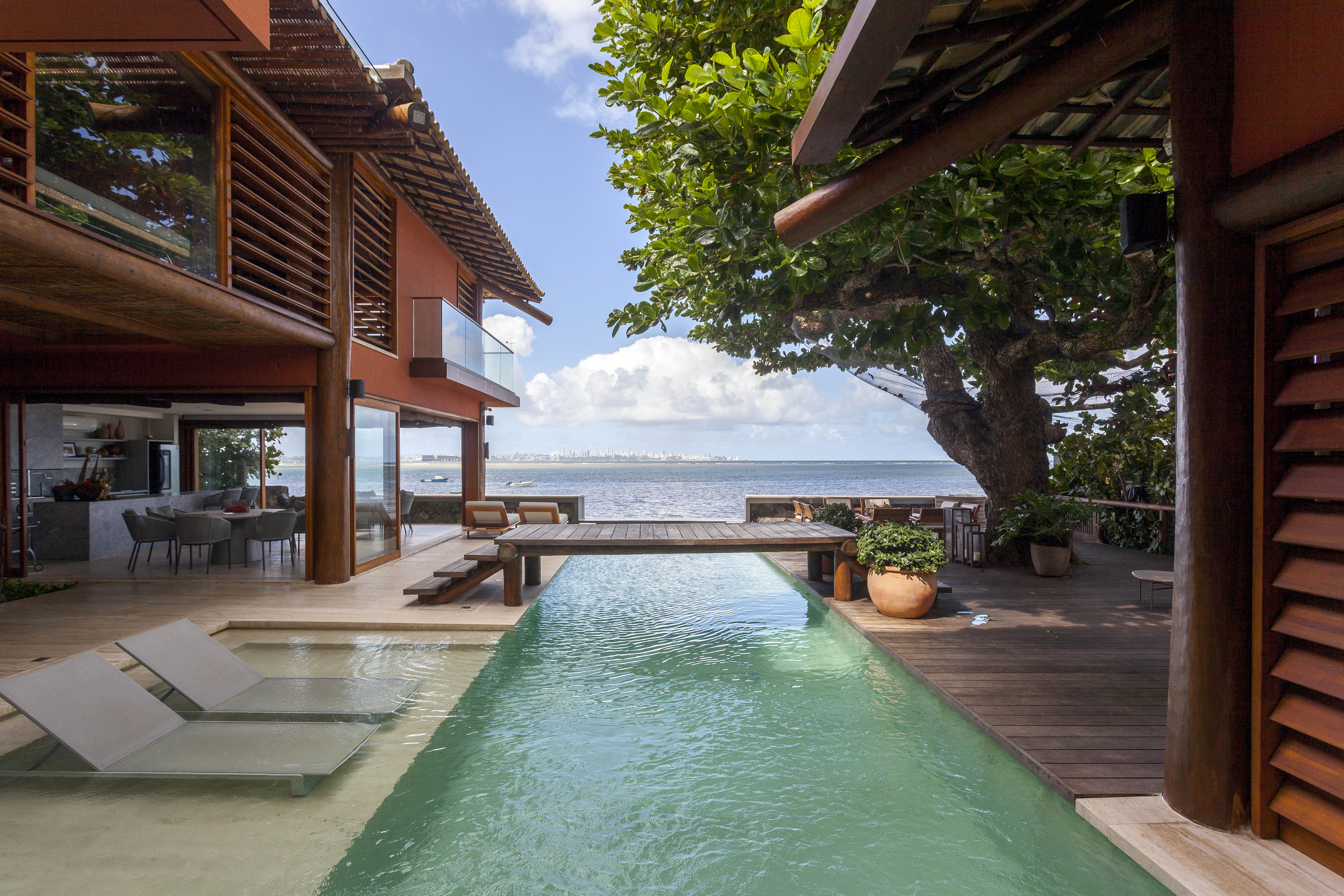 Piscina parece extensão do mar nesta casa assinada por David Bastos. Na foto, piscina com passarela no meio.