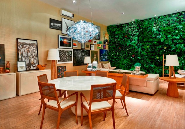 CASACOR Brasília Loft Lake. Miguel Gustavo apresenta um espaço acolhedor com muita madeira e a presença marcante da parede verde. Ele soltou vários móveis das paredes para gerar mais espaços de exibição de telas de arte e fotografias.
