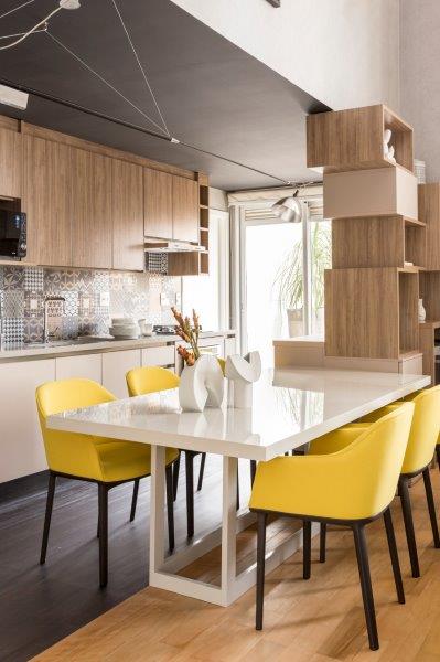 As cadeiras amarelas da cozinha chamam atenção a primeira vista e compõem com o tom ameno da marcenaria.