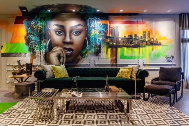 Street Loft - Sandro Jasnievez: neste espaço, o modelo de sofá verde escuro imprime elegância e um certo ar clássico, que contrasta com o mural de grafite, ao fundo.