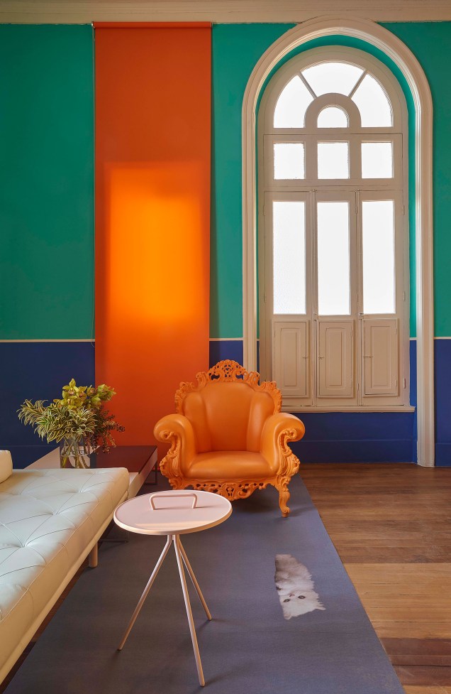 Na <strong>Sala de Imprensa</strong>, de Pedro Lázaro, o azul carbono e o verde piscina permeiam as paredes do espaço, mas o que chama mesmo a atenção e traz calor ao projeto é a icônica <span>cadeira Proust laranja, do mesmo tom do rolô, que equilibra o visual do ambiente.</span>