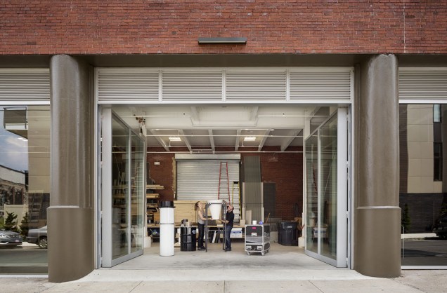 Com altas portas de vidro que abrem a a rua, a oficina pode receber grandes materiais facilmente.