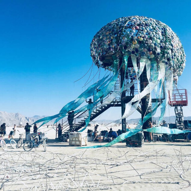 Bloom - Peter Hazel. A água viva de 40 metros, que também esteve presente em 2017, volta ao festival esse ano. Vendo de longe, temos a impressão de que é uma única água viva, mas chegando perto, podemos perceber que é composta por milhares de medusas menores, que nadam em um mar de tentáculos e luzes. O público pôde subir ao topo da cúpula para apreciar a vista do Burning Man.