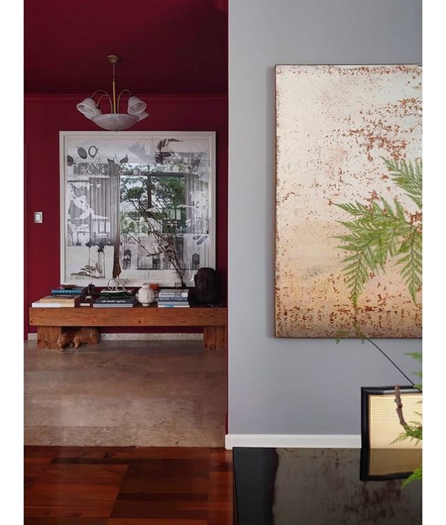 Em planos diferentes, a parede cinza recebe a tela de Clayton Assaf e a parede vermelha, a obra de Marco Magalhães.