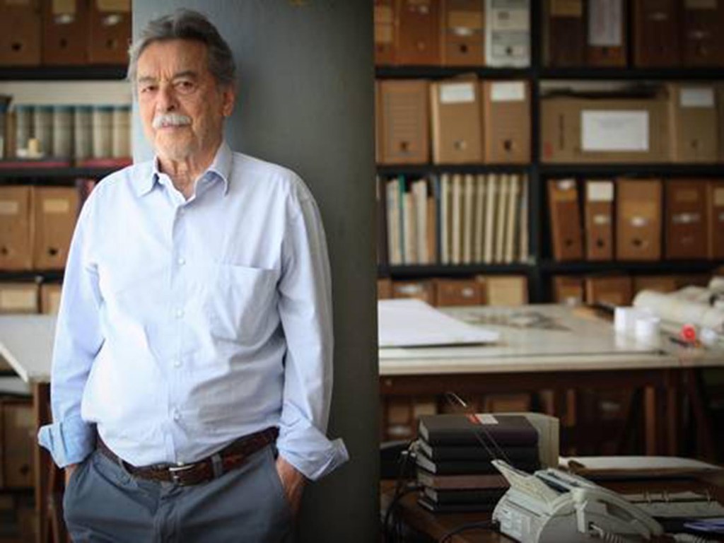 O arquiteto brasileiro Paulo Mendes da Rocha em seu escritório localizado em São Paulo com as mãos no bolso e encostado em uma pilastra