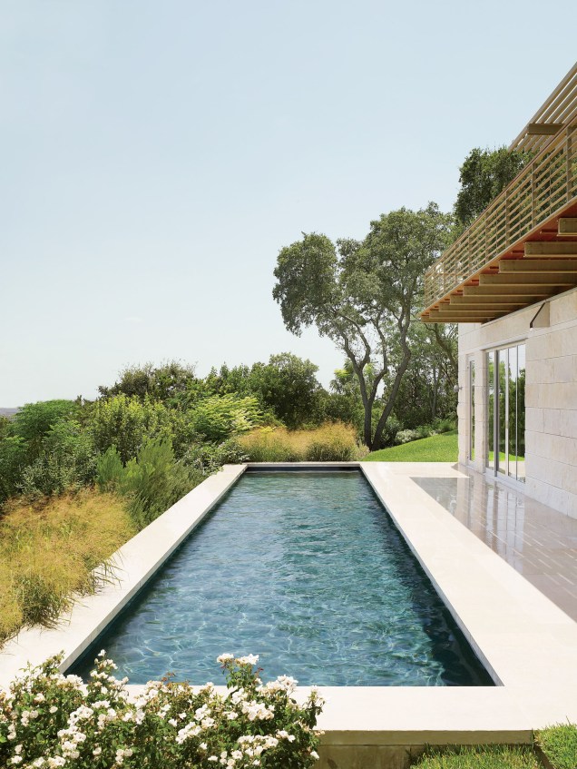 Para criar esta casa na encosta de Austin, o Flato Architects se uniu a Terry Hunziker para construir uma casa minimalista. A piscina olímpica, vista aqui, é cercada por calcário e gramados. Não muito longe fica um gramado, um terraço com sombra de pérgola e um punhado de carvalhos.