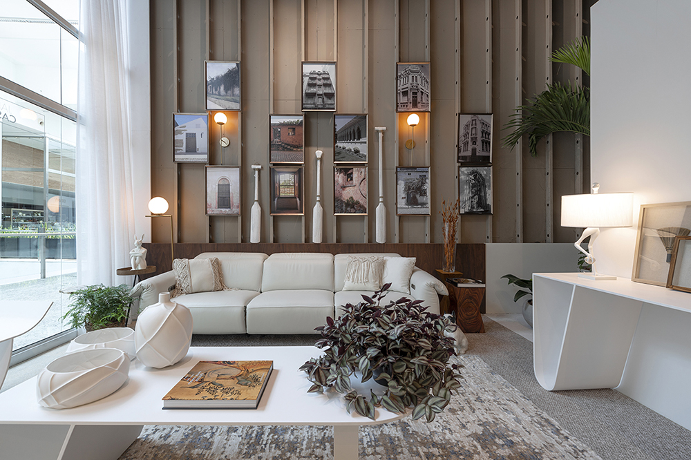 Vista frontal do living com sofá, mesa de centro e parede com fotos e remos