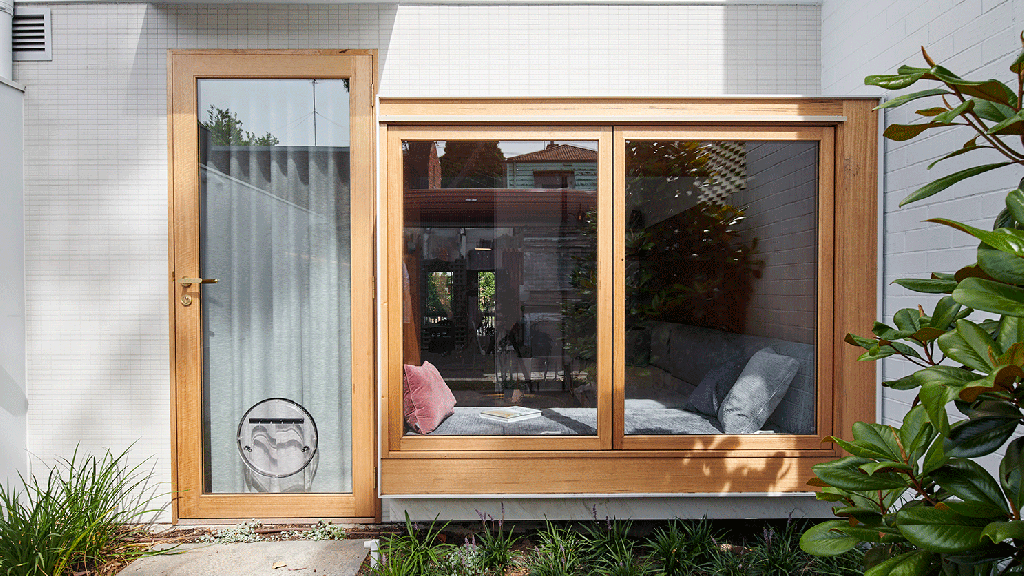 Porta para o quinta vista de fora, um gif com as janelas de vidro e moldura de madeira abrindo. À esquerda, a porta de vidro com moldura em madeira e uma porta redonda para cachorro coberta com uma cortina interna.