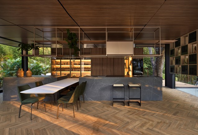 Gourmet dos Sentidos Deca, projeto de Sérgio Vianna para a CASACOR Minas Gerais 2021. Na foto, cozinha com piso com padrão de madeira, mesa, ilha e estante.