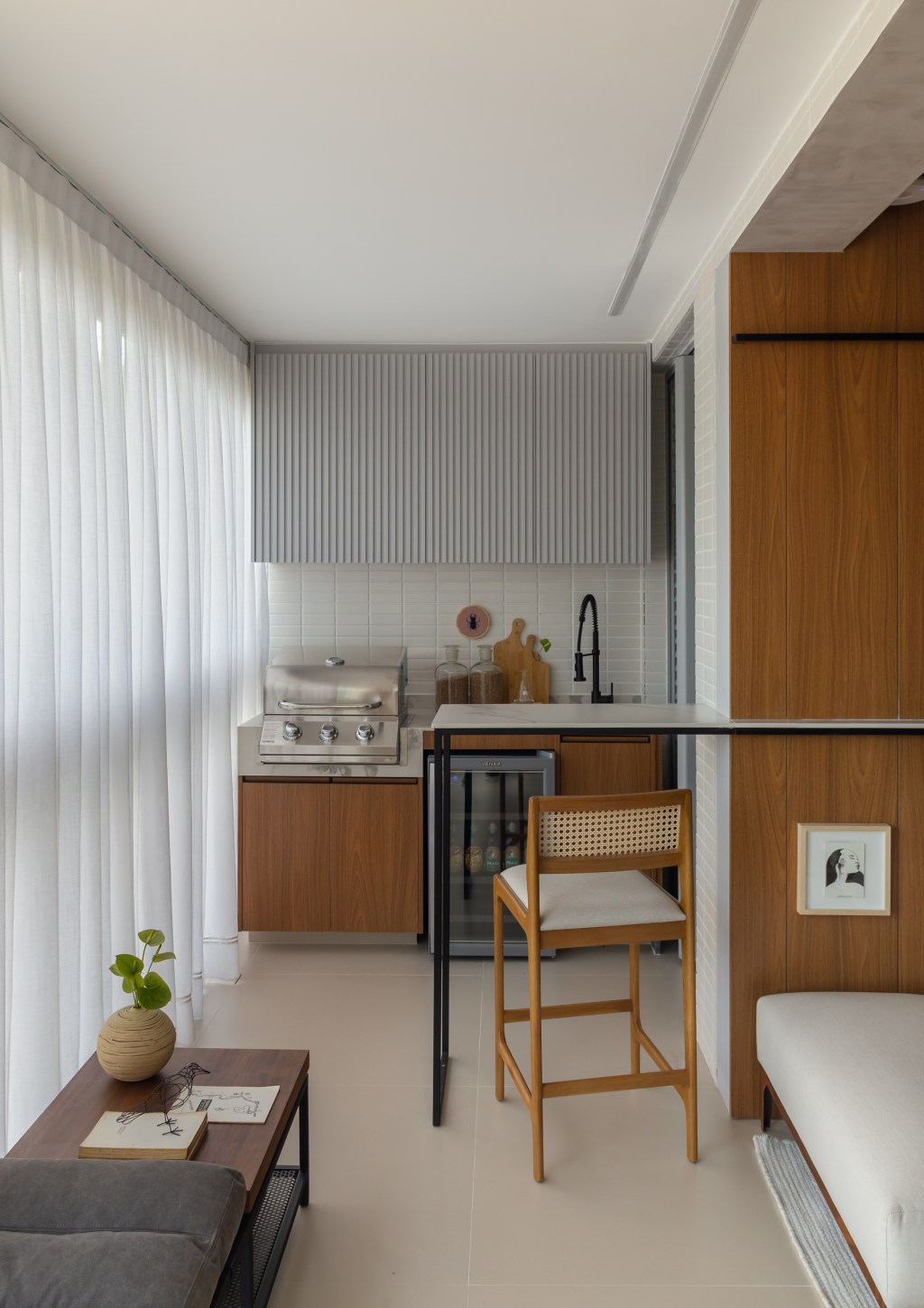Apê de 100 m2 prático décor contemporâneo toques industriais arquiteto Rafael Ramos sala estar varanda banco aparador bancada churrasqueira cozinha cortina