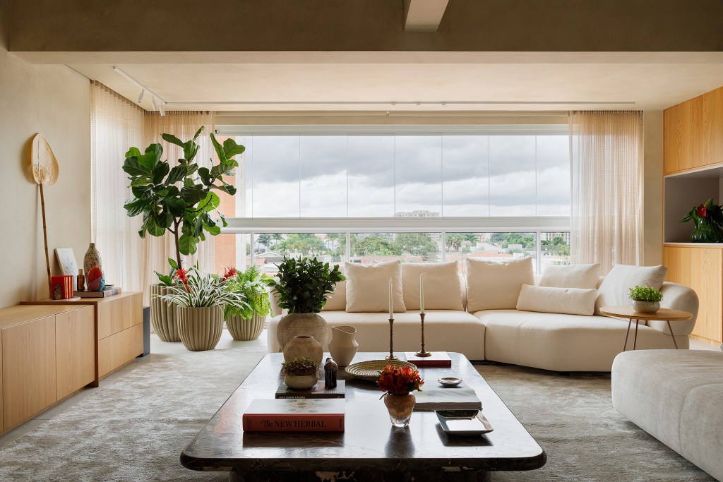 Apê 130 m2 ar mediterrâneo formas orgânicas Gustavo Marasca varanda sala estante mesa sofa tapete cortina varanda