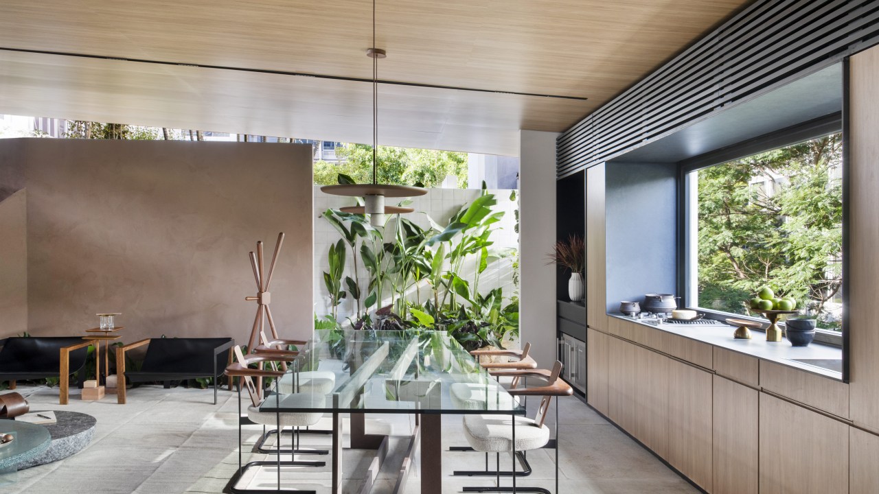 Navarro Arquitetura - Casa Araxá. Projeto da CASACOR São Paulo 2023. NA foto, sala de jantar com mesa de vidro, cozinha e jardim.