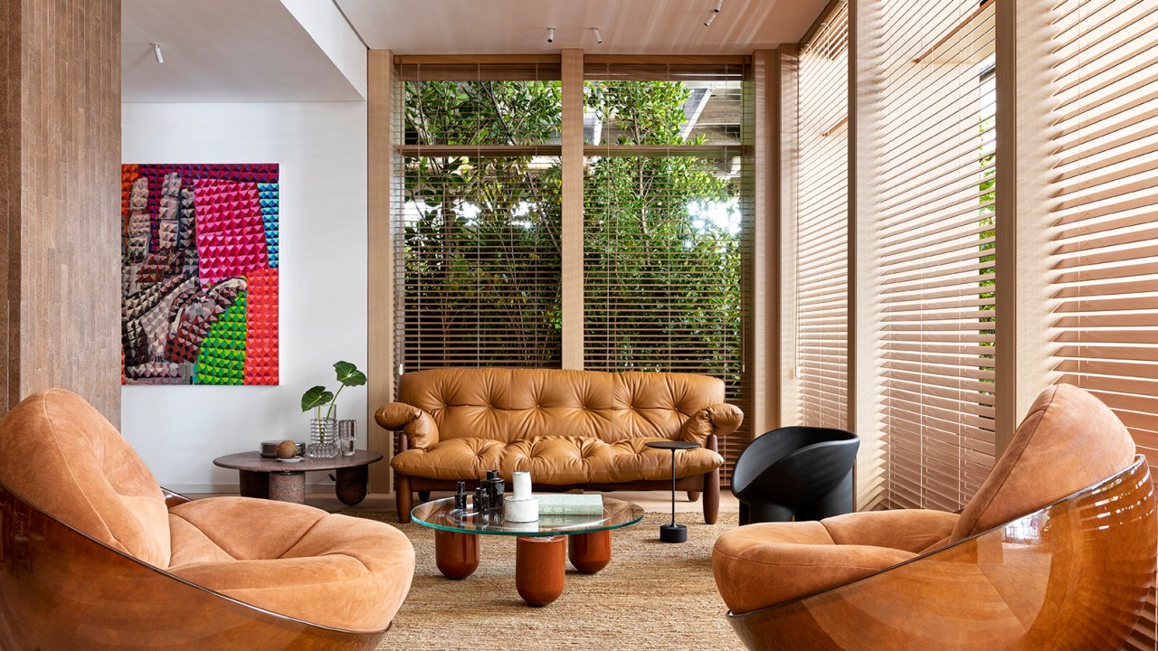 Tufi Mousse Arquitetura - A Casa Morena. Projeto da CASACOR São Paulo 2023. Na foto, sala com sofa de couro, persianas e tapete.