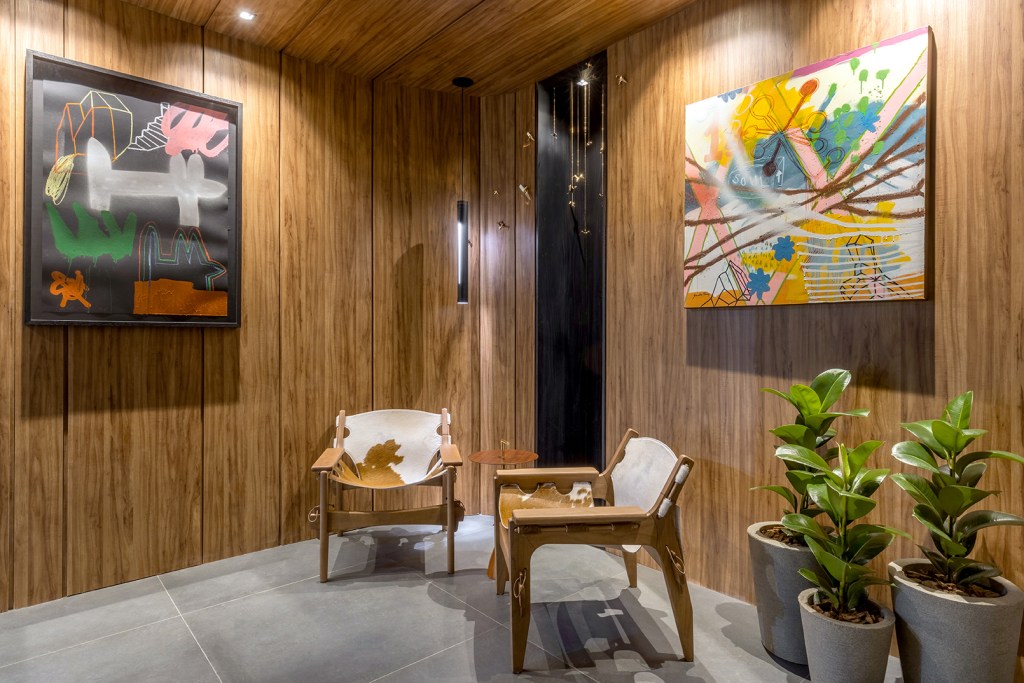 Allan Sávio Arquitetura - Thisa Experience. Projeto da CASACOR Goiás 2023. Na foto, lounge com quadros, poltronas e parede de madeira.