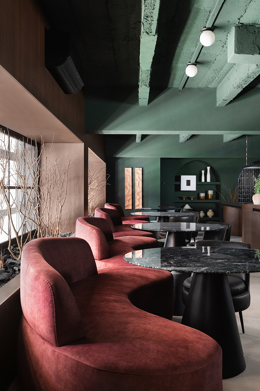 Altera Arquitetura - Ninho & Aspargos. Projeto da CASACOR São Paulo 2023. Na foto, restaurante com mesas pretas, sofás vermelhos e jogo de luz.