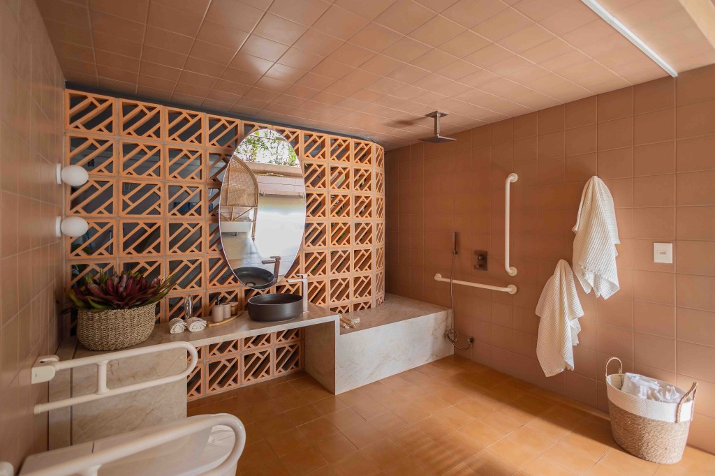 ARQTAB | Maycon Fogliene - A Casa do Ser. Projeto da CASACOR São Paulo 2023. Na foto, banheiro acessível como parede de cobogó, espelho e chuveiro de teto.