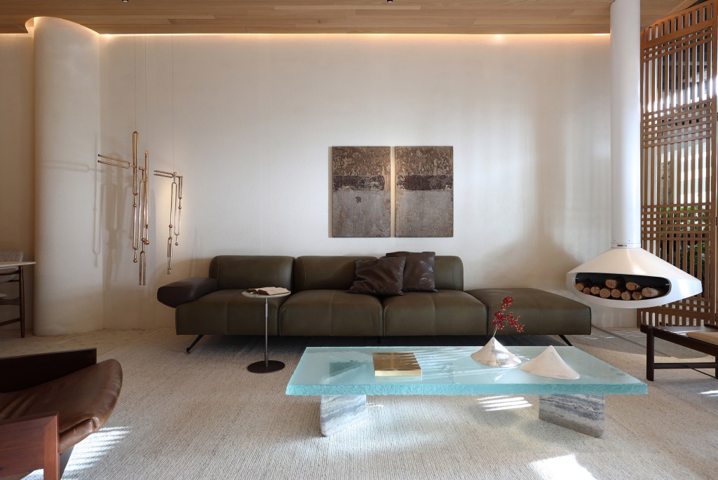 Barbara Dundes Arquitetura - Casa Morada. Projeto da CASACOR São Paulo 2023. Na foto, sala de estar com sofá verde, lareira e divisória vazada.