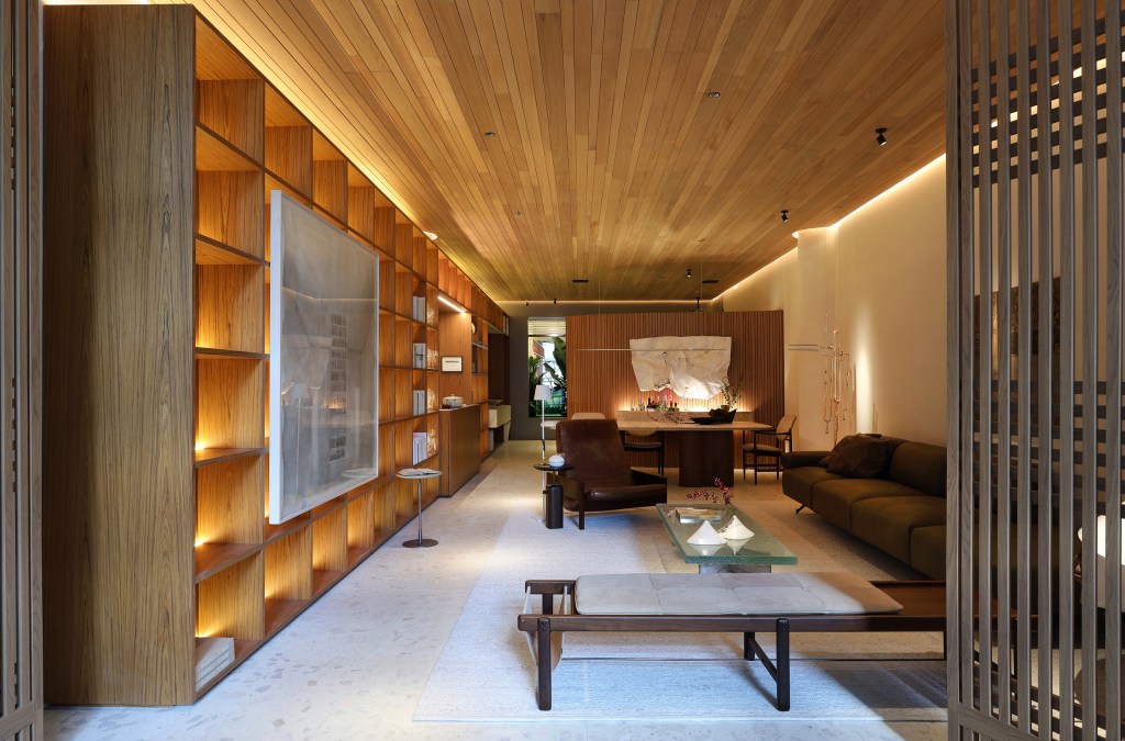 Barbara Dundes Arquitetura - Casa Morada. Projeto da CASACOR São Paulo 2023. Na foto, sala de estar com sofá verde, estante iluminada e e jantar integrado.