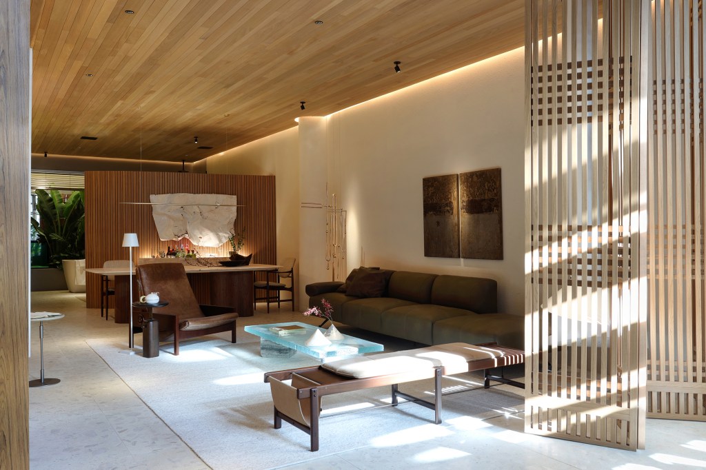 Barbara Dundes Arquitetura - Casa Morada. Projeto da CASACOR São Paulo 2023. Na foto, sala de estar com sofá verde, lareira e divisória vazada.