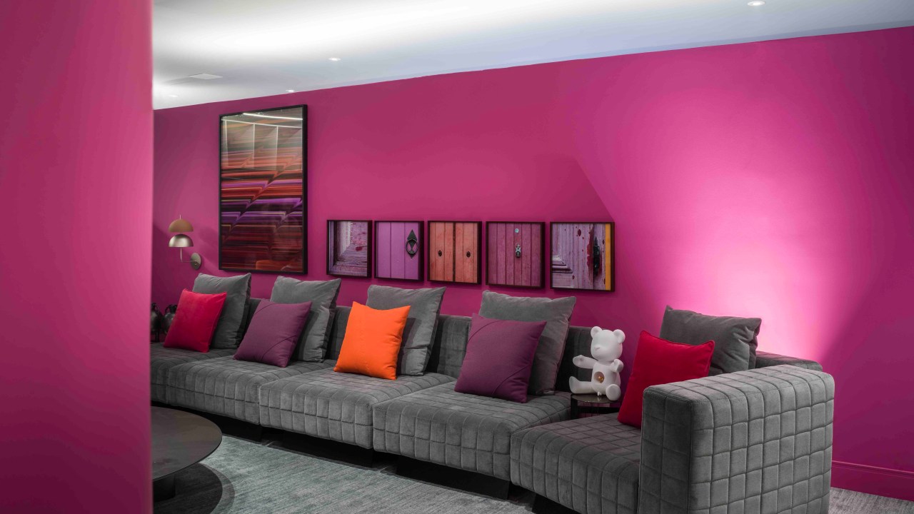 Brunete Fraccaroli Arquitetura & Interiores - O Reverso do Metaverso. Projeto da CASACOR São Paulo 2023. Na foto, sala com parede rosa, sofá cinza e obras de arte.