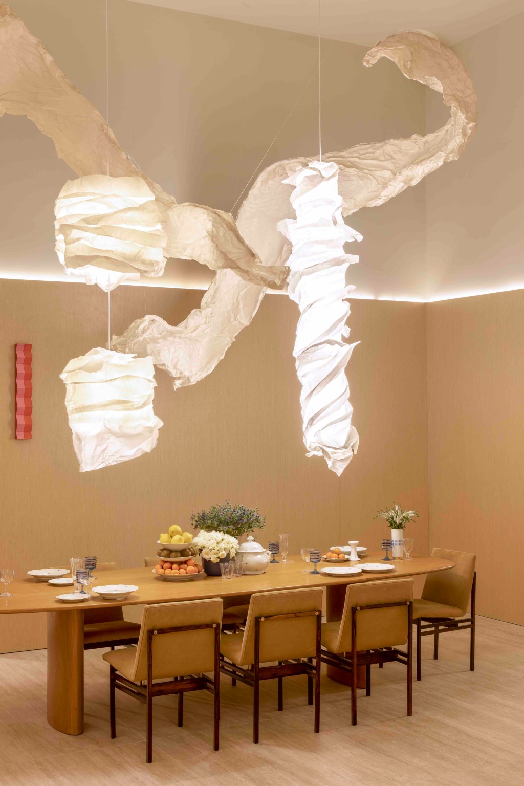 Da Hora Arquitetura - Loft Vastu. Projeto da CASACOR São Paulo 2023. Na foto, sala de jantar com luminária orgânica, estante de madeira e pé-direito duplo.