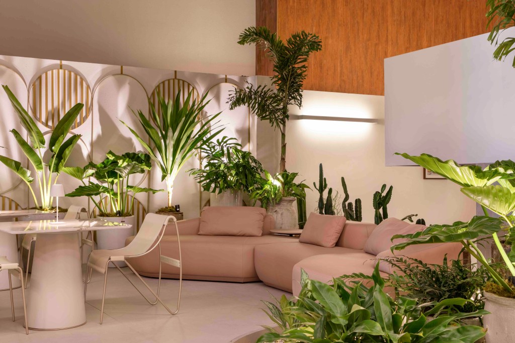 Fernanda Rubatino Arquitetura - Savoir-faire Café. Projeto da CASACOR São Paulo 2023. Na foto, café com sofá curvo, plantas e mesas e cadeiras claras.