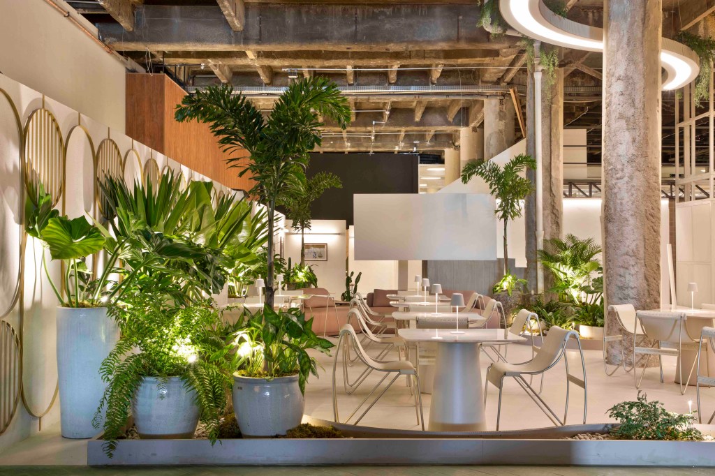 Fernanda Rubatino Arquitetura - Savoir-faire Café. Projeto da CASACOR São Paulo 2023. Na foto, café com sofá curvo, plantas e mesas e cadeiras claras.