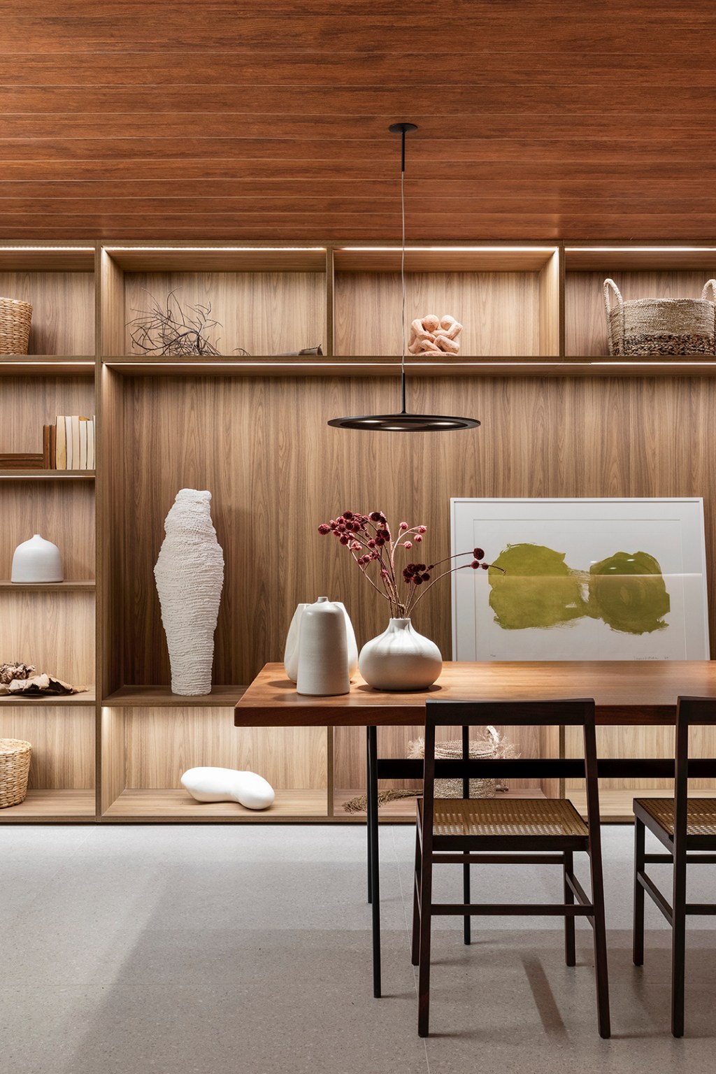 GDL Arquitetura - Galeria Origami CASACOR. Projeto da CASACOR São Paulo 2023. Na foto, sala com estante, mesa de madeira e obras de arte.
