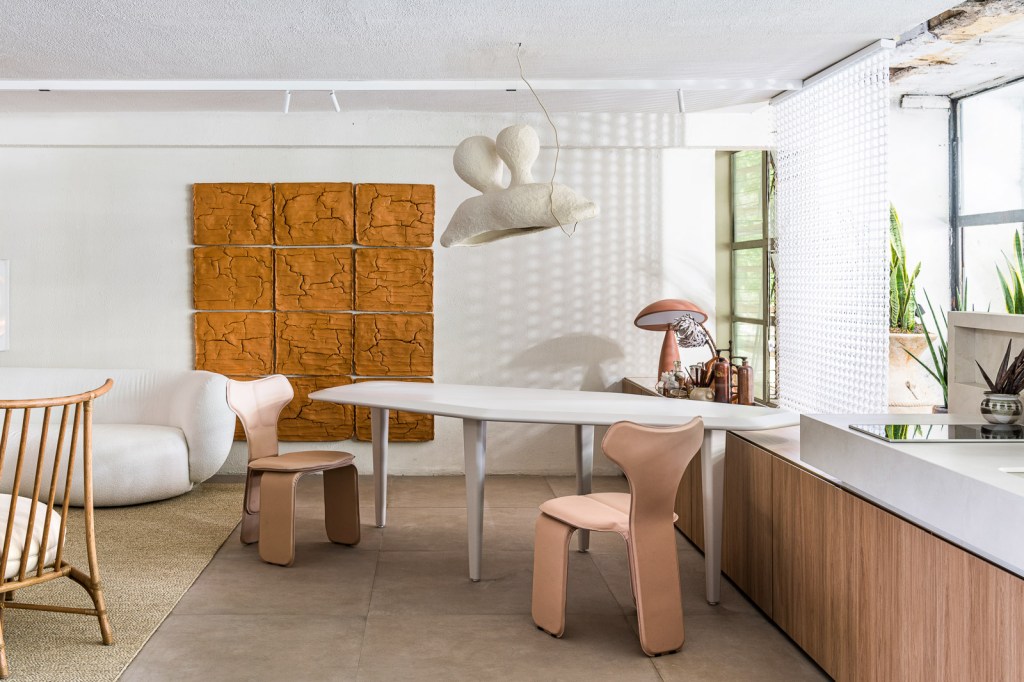 Gustavo Martins Arquitetos - Odoiá. Projeto da CASACOR São Paulo 2023. Na foto, sala de jantar com mesa geométrica e quadro de lama.
