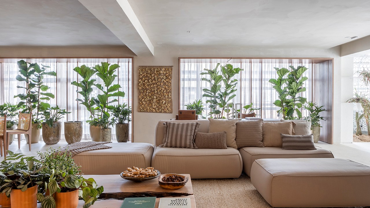 Isabella Nalon Arquitetura e Interiores - Refúgio Conexão. Projeto da CASACOR São Paulo 2023. Na foto, sala de estar com sofa em L, plantas, mesa e tapete.