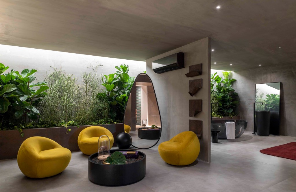 Léo Shehtman - Memórias. Projeto da CASACOR São Paulo 2023. Na foto, sala com poltronas amarelas, espelho orgânico e jardim.